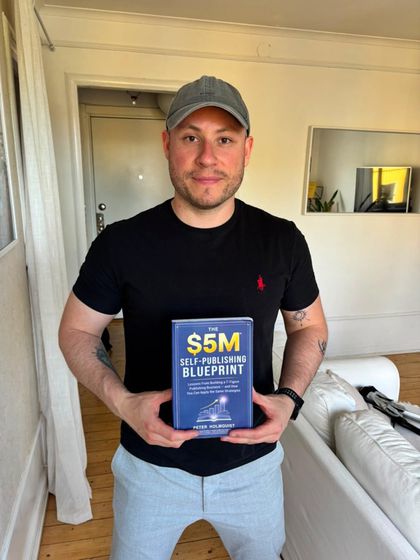 Carlos, a DPE member, holding The $5M Self-Publishing Blueprint